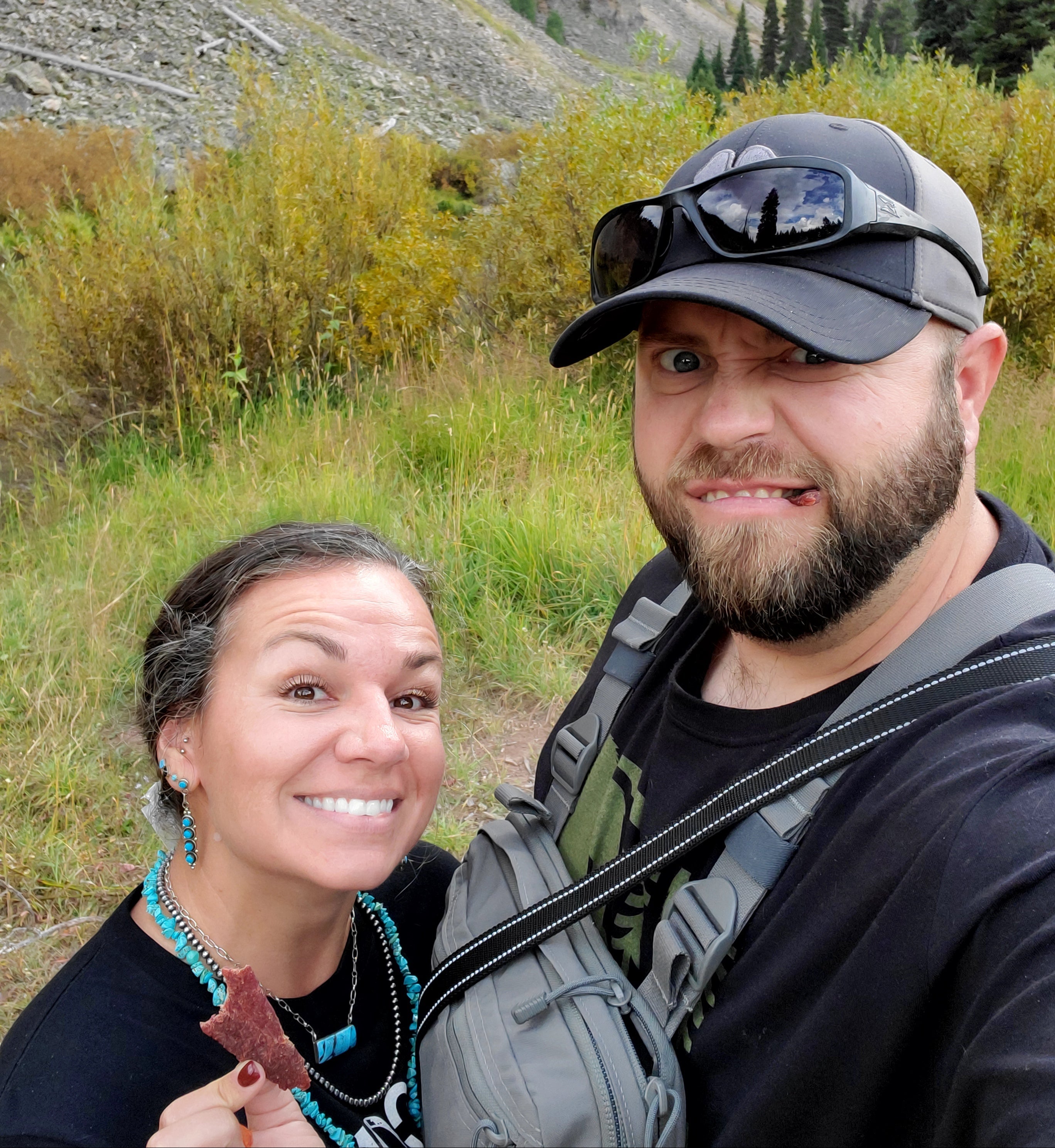 Beef tallow maker and her husband taking a selfie in a mountainous area with greenery and rocks.