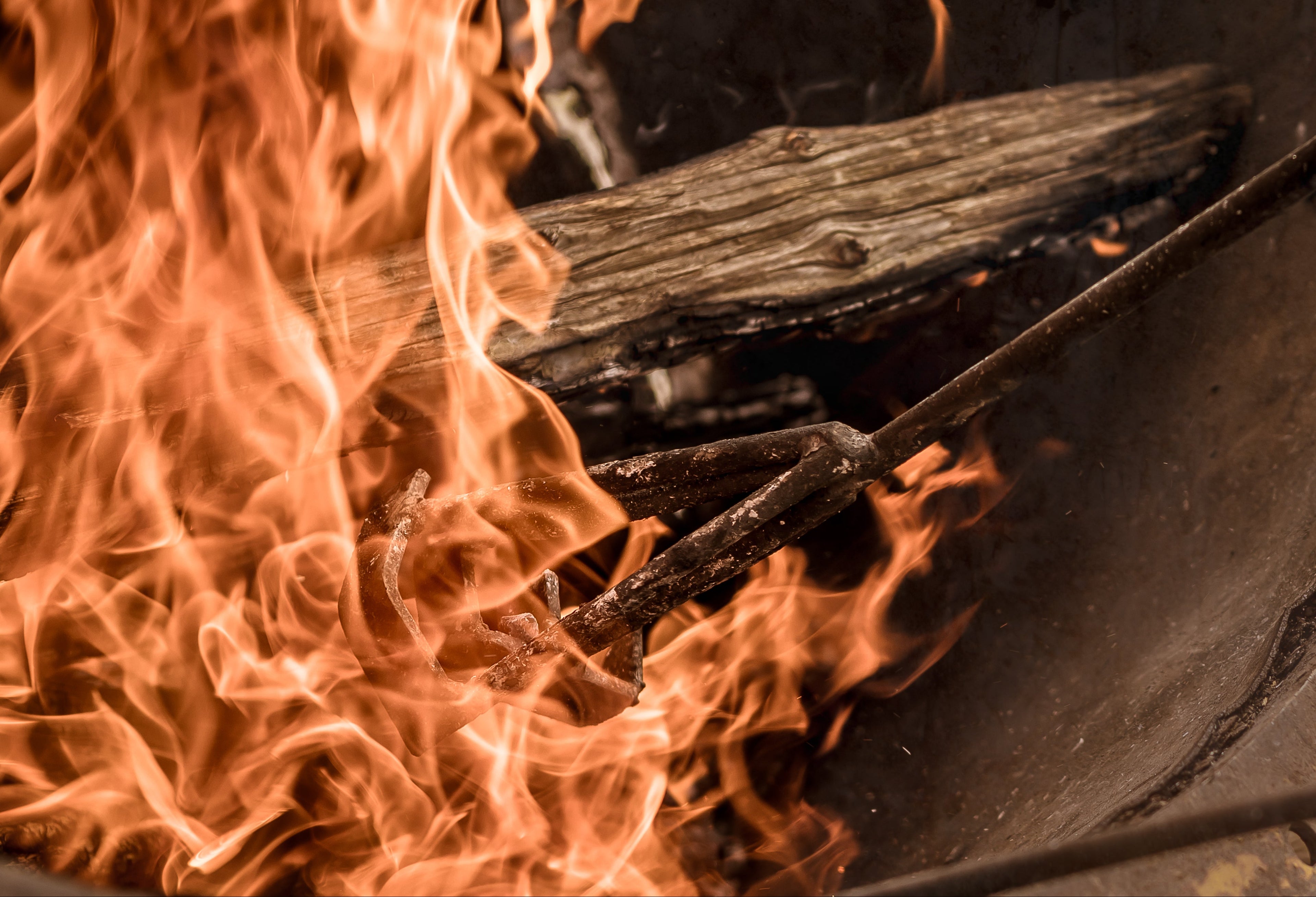 Beef branding iron in fire with burning log