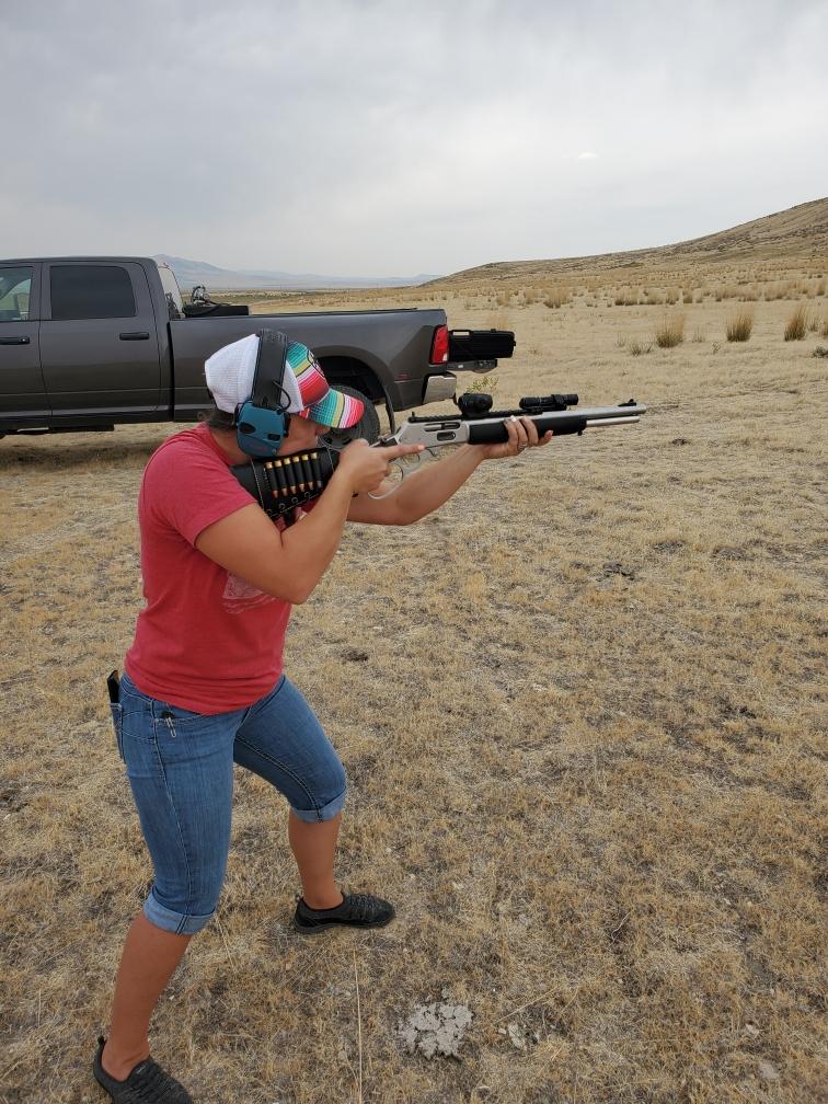 Beef tallow maker holding a rifle in an open field with a truck in the background